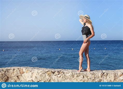 Young Pretty Hot Attractive Girl Relaxing In Swimsuit On Stones With Blue Sea And Sky On