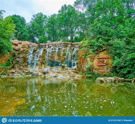 The Scenic Waterfall Among The Lush Greenery Of Landscape Garden In