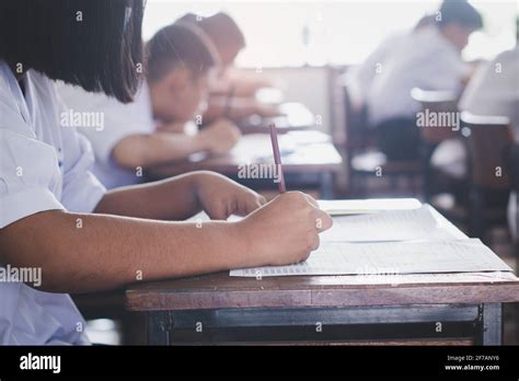 Students Taking Exam And Writing Answer In Classroom With Stress