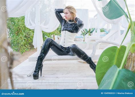 Jeune Fille Blonde Mince D Esclavage Dans La Combinaison Pantalon Noire De Latex Avec Le Corset