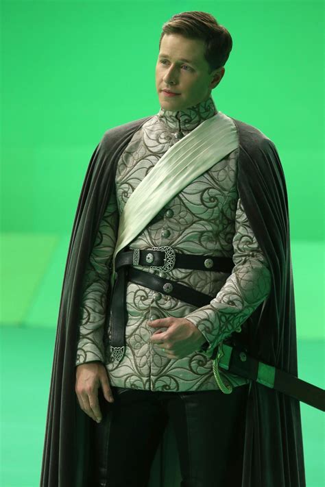 A Man Dressed In Costume Standing Next To A Green Screen With His Hands