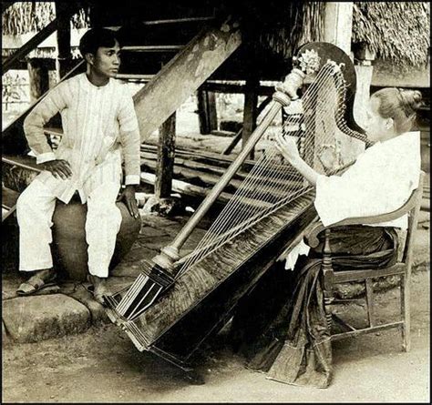 An Old Photo Of Two Men Sitting Down Playing Musical Instruments In