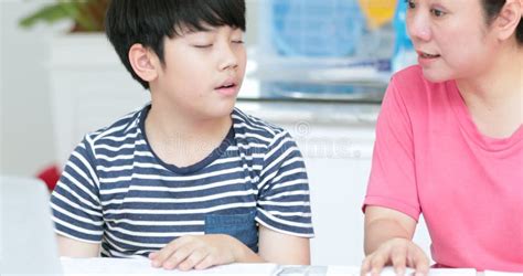 Serious Asian Mother With Son Doing Homework In The Living Room Stock