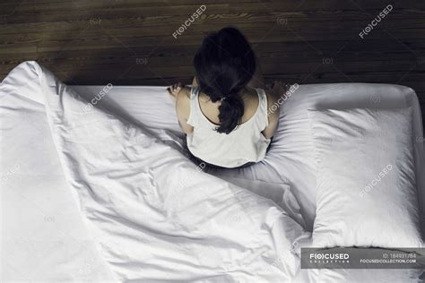 Overhead View Of Woman Sitting On Edge Of Bed — Sleepy Bedsheet