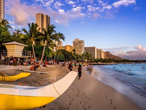 Tourist Sunbathing And Surfing On The Waikiki Beach In Hawaii