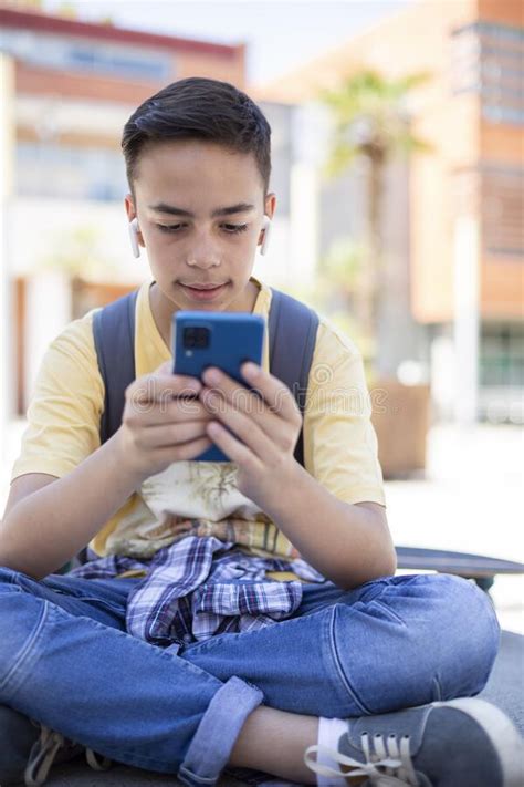 Portrait Of Caucasian Teenage Student Boy Using Mobile Phone Outdoors