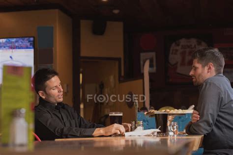 Friends Talking With Each Other While Having Drinks In Pub — Pizza