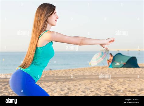 Portrait Of Sportswoman Which Is Doing Excercises For Warm Up On The Beach Near Sea Stock Photo