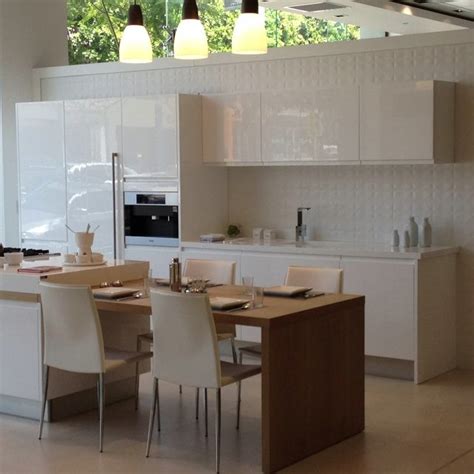 Warm woods contrast with white cabinets to create an inviting space. Porcelanosa | Kitchen, Beach kitchens, Kitchen cabinets