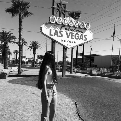 A Woman Standing In Front Of The Las Vegas Sign With Her Back Turned To The Camera