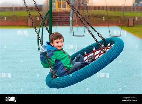 A Happy Young Boy Playing On A Park Swing Stock Photo Alamy