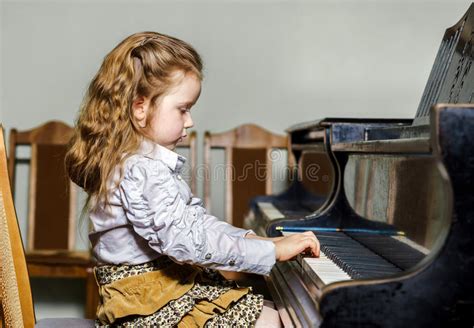 Cute Little Girl Playing Grand Piano In Music School Stock Photo