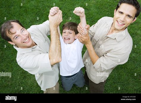 Two Men Holding Up Little Boy By His Arms All Smiling High Angle View