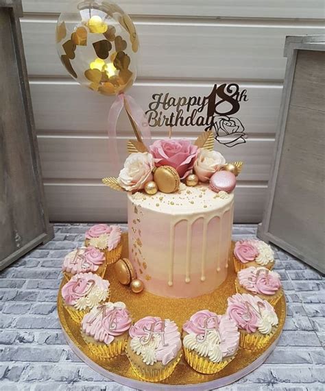 A Pink And Gold Birthday Cake With Cupcakes