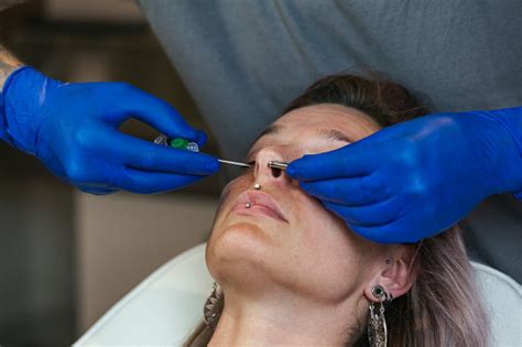 Portrait Of A Woman Getting Her Nose Pierced Man Showing A Process Of