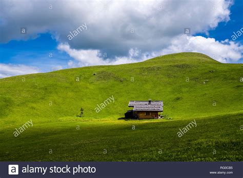 Hilly Agricultural Countryside With Green Pastures And Wooden Houses At