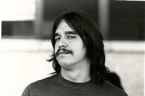 A Black And White Photo Of A Man With Long Hair Wearing A Moustache