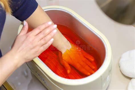 Paraffin Theoraphy Female Hand And Orange Paraffin Wax In Bowl
