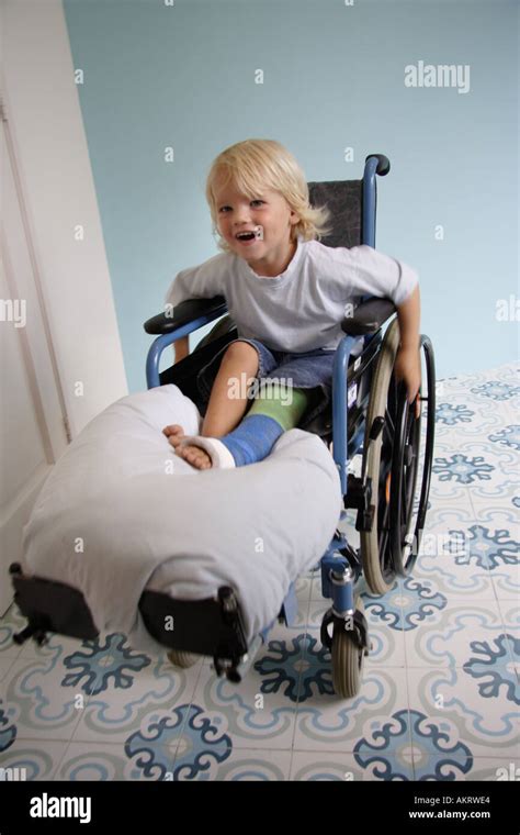 Little Boy With A Broken Leg Sitting In A Wheelchair Stock Photo