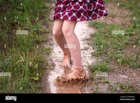 Barefoot Girl Walks Through A Puddles Of Water After The Summer Rain In