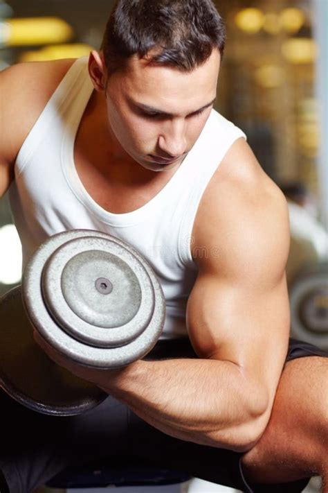 Strengthening His Biceps A Muscular Young Man Working Out In The Gym