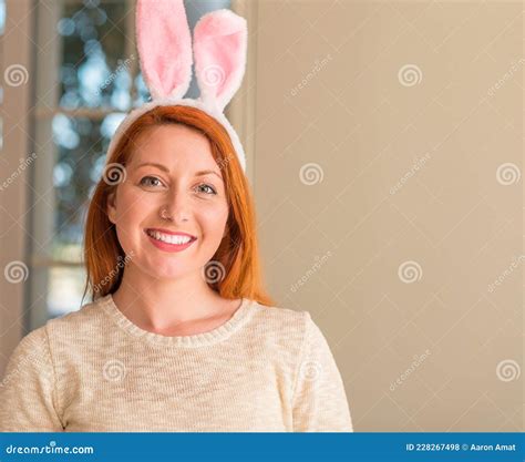 Redhead Woman Wearing Easter Rabbit Ears At Home With A Happy Face