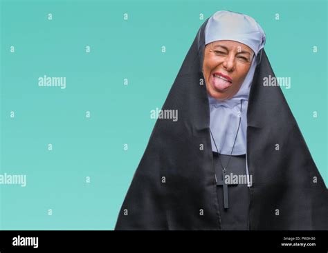 middle age senior christian catholic nun woman over isolated background sticking tongue out