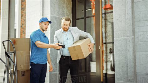 Delivery Man Gives Postal Package To A Business Customer Who Signs Electronic Signature POD