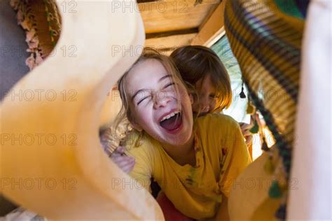 caucasian brother and sister laughing under table photo12 tetra images marc romanelli