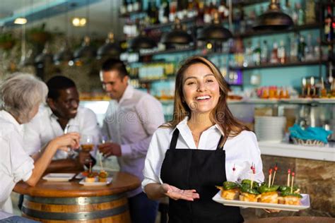 Cheerful Smiling Female Waiter Holding Served Tray Meeting Visitors At
