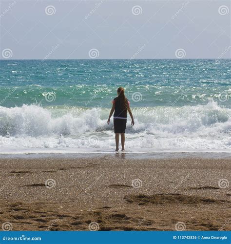 A Young Girl Stands On The Beach Near The Blue Sea Stock Photo Image