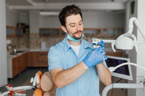 Free Photo Handsome Young Dentist In White Coat Is Holding Plastic