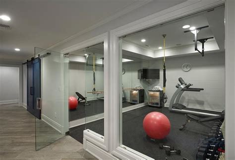 A Glass Door Opens To A Basement Home Gym Filled With A Mirrored Accent