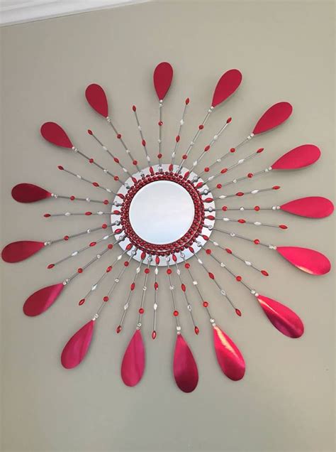 A Circular Mirror With Red Spoons Hanging On The Wall