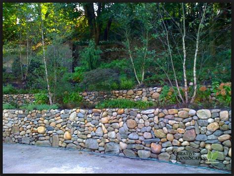 A retaining wall is a feature that is practical, first and foremost. round river rock multi colored. | Stone walls garden, Dry ...