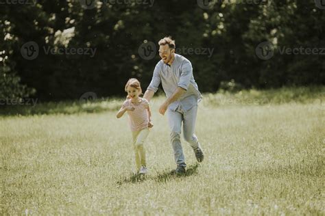 Father Chasing His Little Daughter While Playing In The Park 2879406