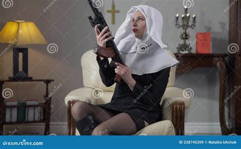 Portrait Of Slim Gorgeous Provocative Woman In Nun Costume And Stockings Caressing Hunting Gun