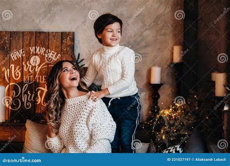 Mom And Son Are Sitting At Home On The Couch Before The New Year And Smiling Together Stock