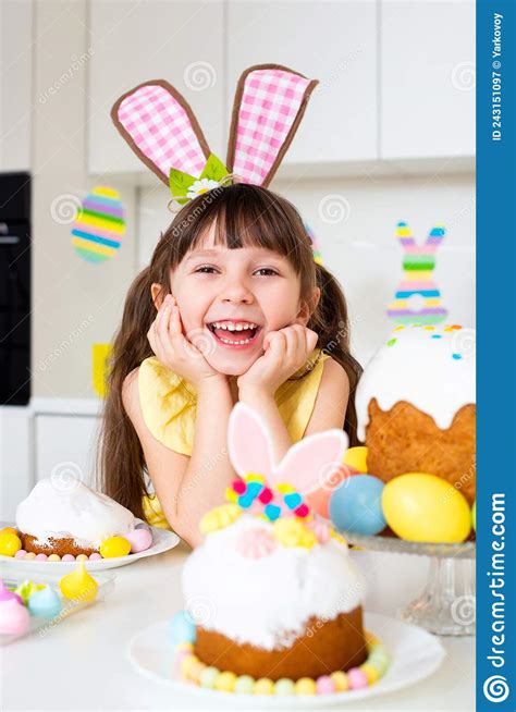 A Cute Smiling Little Girl With Bunny Ears Prepares An Easter Cake And