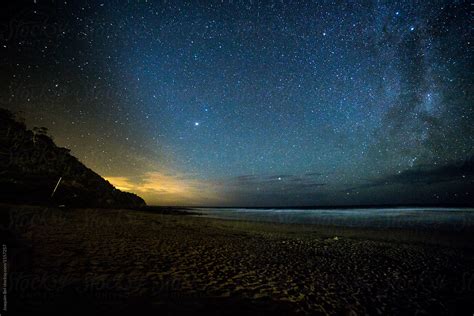 Stars Over A Beach With Lights Afar By Stocksy Contributor Joaquim