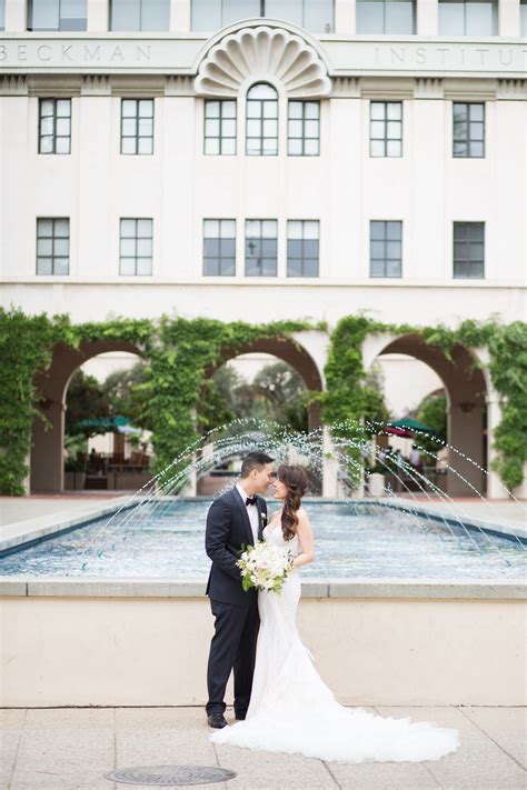 A Bride And Groom Standing In Front Of A Fountain