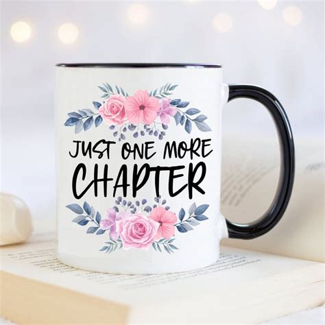a coffee mug with the words just one more charter on it next to an open book