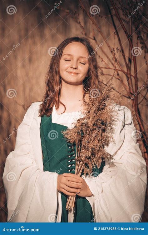 Happy Medieval Young Woman In Historical Female Costume With Reeds