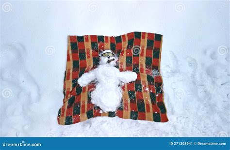 A Snowman Lying With Arms Outstretched On His Back On A Blanket And