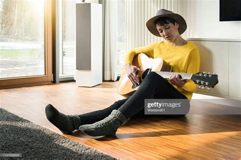 Woman Sitting On The Floor Of Living Room Playing Guitar Sitting Pose