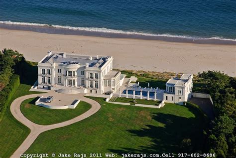 An Aerial View Of A Large White House On The Beach With Trees And Grass