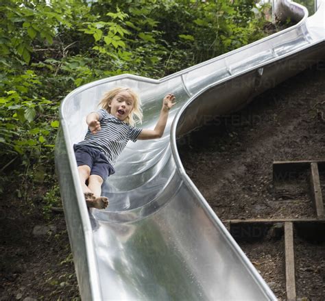 Boy Sliding Down Playground Slide Stock Photo