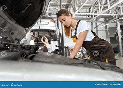 Female Mechanic In White Shirt And Coverall Repairing Engine Stock