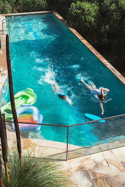 Two Girls Swimming In A Backyard Pool Del Colaborador De Stocksy