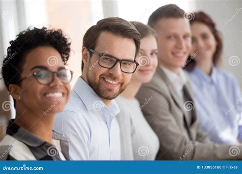 Portrait Of Smiling Employees Sit In Row Looking At Camera Stock Photo